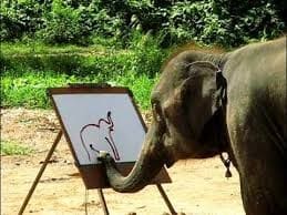 An elephant holding a paintbrush in its trunk, painting on a white canvas set on an easel outdoors.